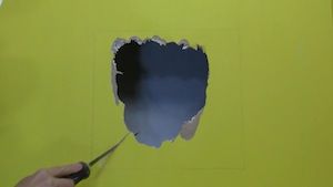 photo cutting out a drywall hole with a saw
