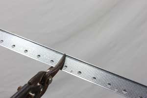 photo cutting metal drywall corner bead with tin snips