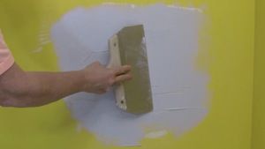 photo smoothing a second coat of joint compound over a drywall patch